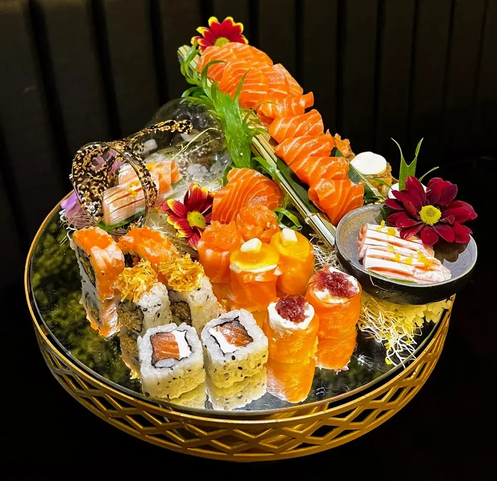 Combinado Natsumi com sashimi de salmão, joes com cream cheese e geleia, uramakis e hot rolls em uma bandeja dourada
